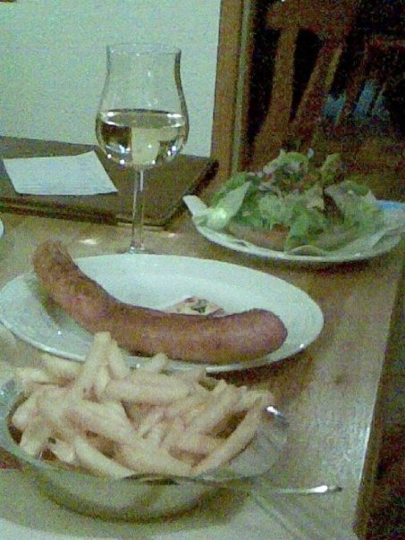 A German meal with sausage, fries, salad and wine
